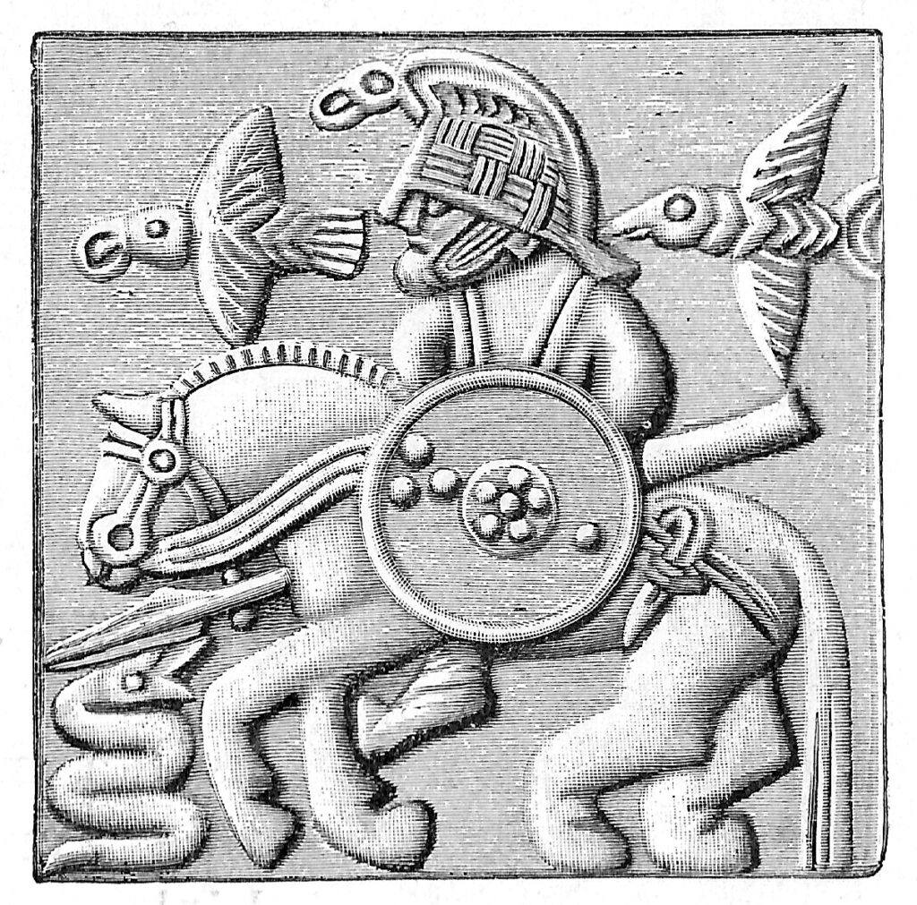 Fra en hjelm-plade, fundet i Vendel, Sverige (fra 600-tallet). De to fugle (formentlig ravne) leder tankerne hen på Odin, som dog ofte afbildes på sin ottebenede hest, Sleipner. Hjelmen bærer også tydeligt præg af en fugl, måske også en ravn, og det er nærliggende at se mere af en identifikation imellem krigeren (eller Odin) og fuglen på hjelmen end en blot og bar pryd-figur