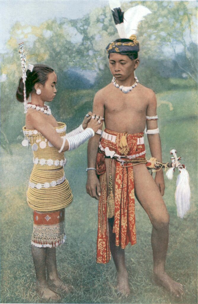 Iban-folk, måske en ung mand og hans hustru. Det var et krav til bejleren, at han havde skaffet et hoved til kraniekulten. Fotoet er fra 1912, men farvelagt et årti senere (foto: Wikimedia Commons, public domain)